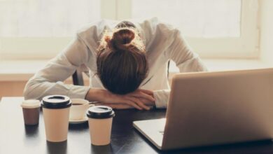 sleepy office worker at desk with multiple coffees